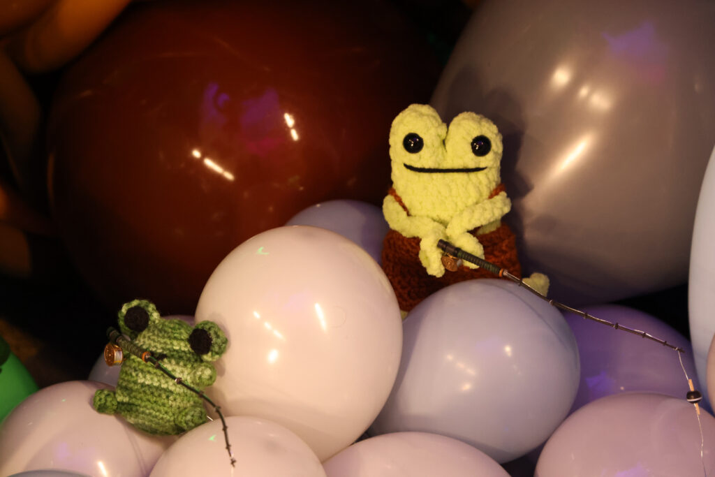 two crochet frogs sitting on balloons and holding fishing poles