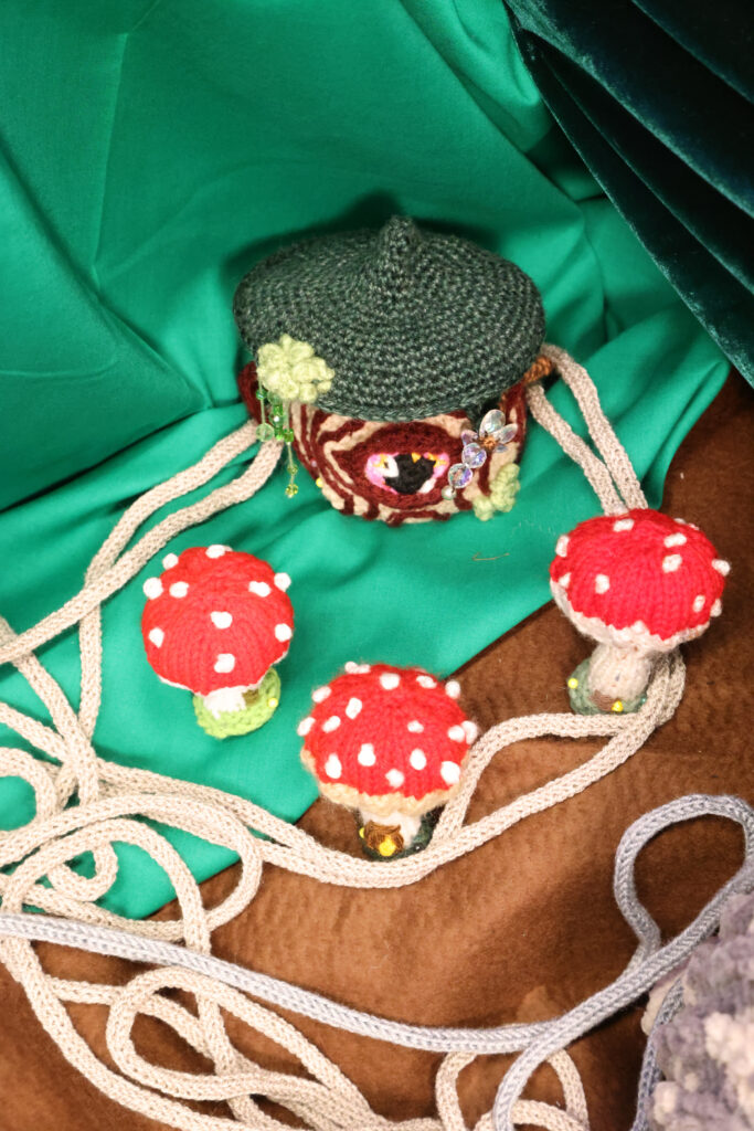 Crochet mushroom house soft sculpture surrounded by three smaller crochet mushrooms