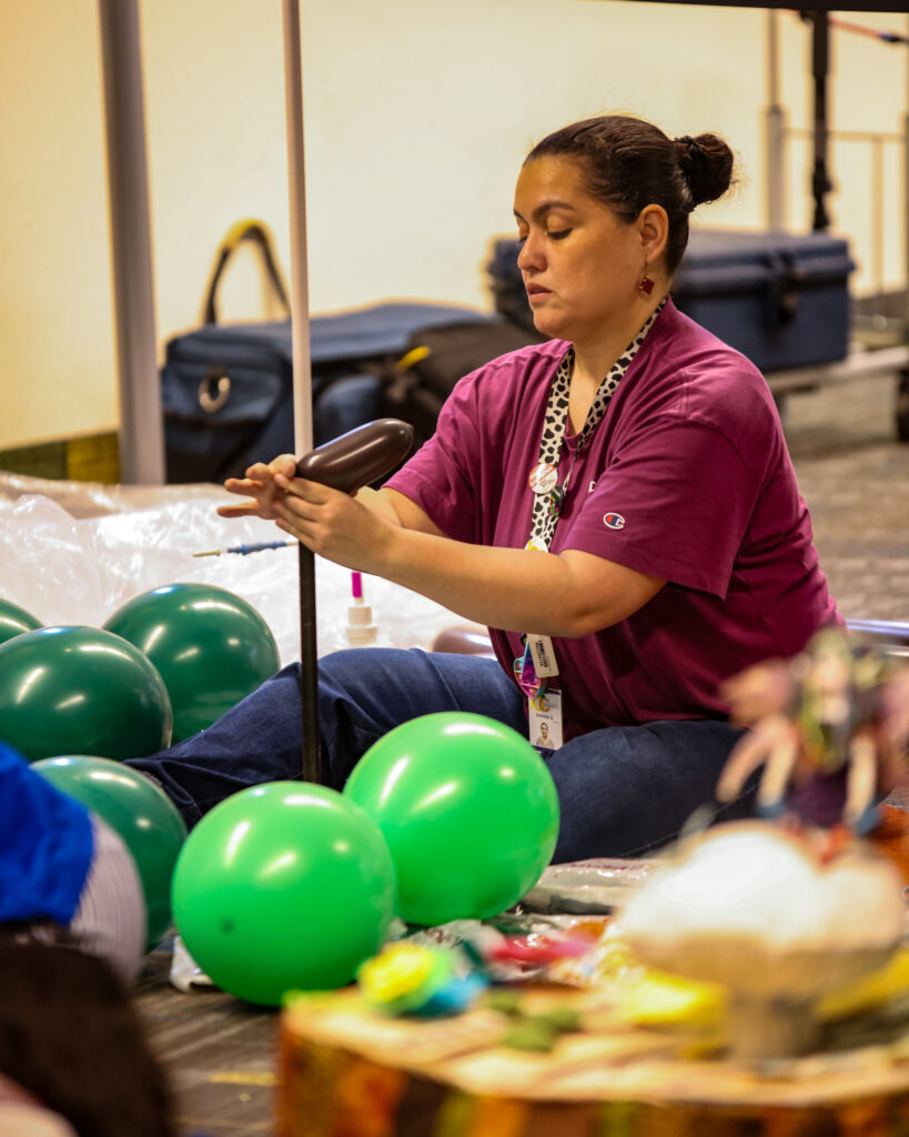 Woman sitting on the floor building an armature for a balloon installation.