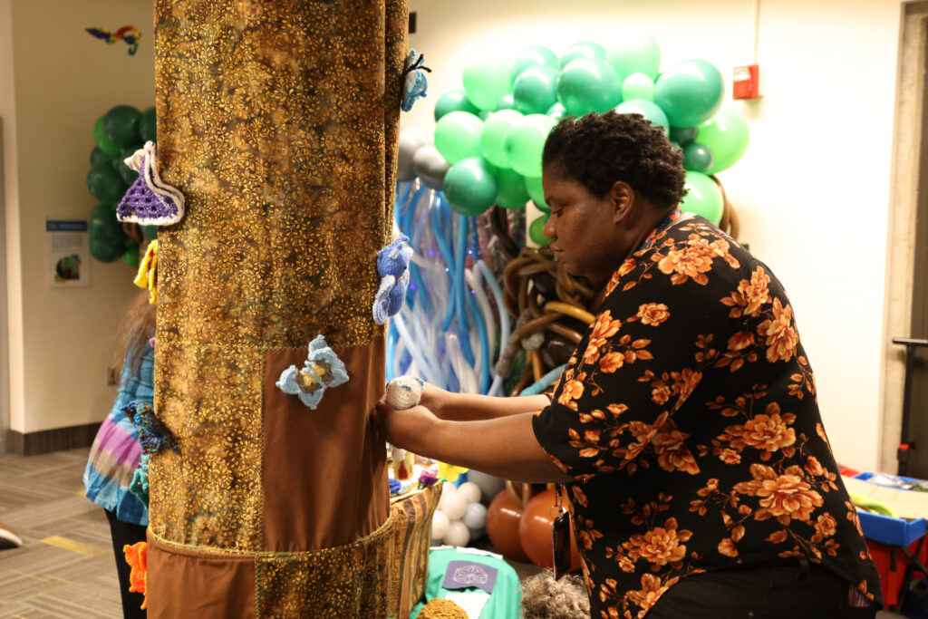 Woman attaching crocheted butterfly to a fabric tree