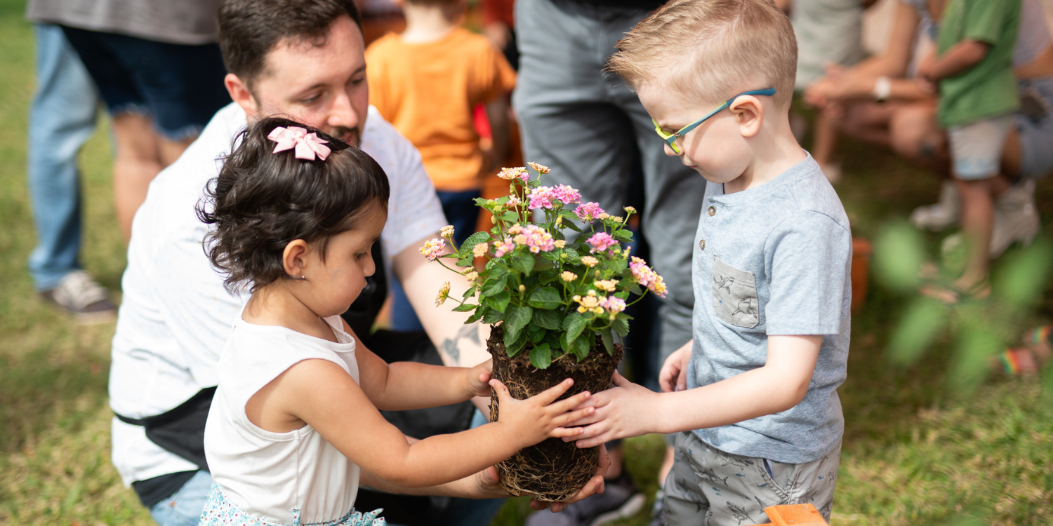 Two children holding a lantana plant