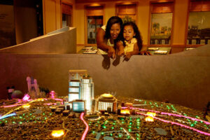 A mother and daughter looking at a lighted scale diorama of Central Florida landmarks on display at the Orange County Regional History Center.