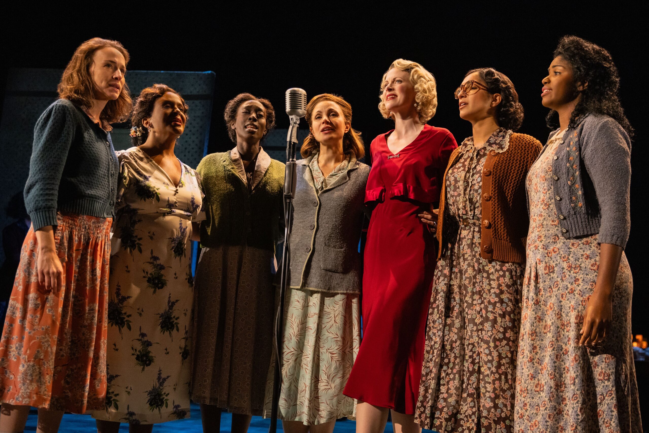 Cast of The Girl From North Country. Group of women standing around a microphone singing.