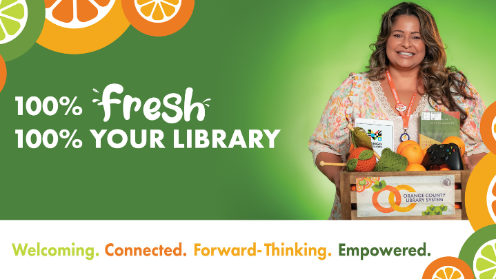 Top Text: 100% Fresh. 100% Your Library.Bottom Text: Welcoming. Connected. Forward-Thinking. Empowered.Graphics: Phot of a woman with long, curly brown hair and tan skin wearing a colorful dress and holding a wooden crate filled with a knitted orange, an xbox controller, a book. Front of box has label with the Orange County Library System logo. Image has green background gradient with illustrated orange slices bordering the top left and bottom right corners.