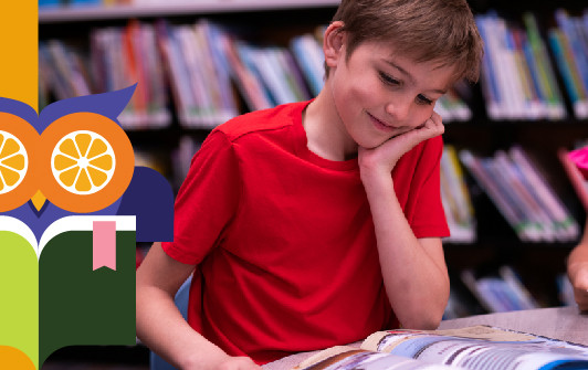 A boy sitting down reading a book.