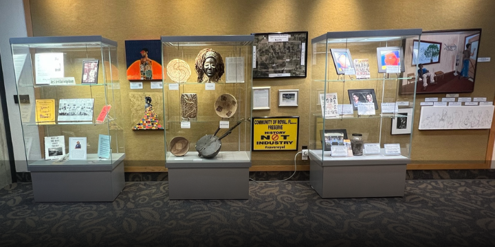 three glass display cases and art mounted to walls encompass the Land & Lineage exhibit