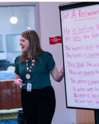 Woman standing at flip chart teaching vocabulary and verb conjugation