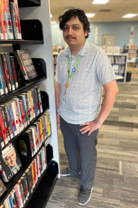 Male OCLS employee stands next to bookshelf