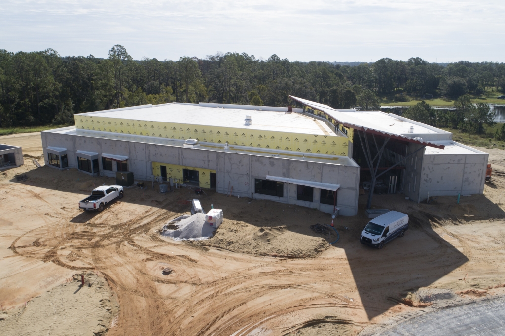 Aerial view from the front of Horizon West construction site with concrete walls, yellow insulation, two parked vehicles, and surrounding dirt terrain.