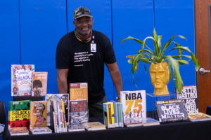 Ricardo Burney stands behind table with book display
