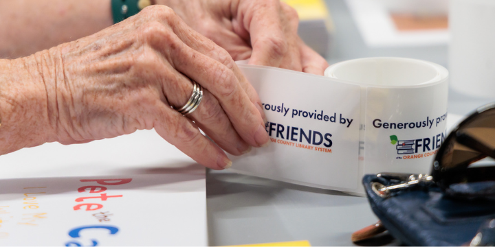 Volunteer hands peel book plate label off roll