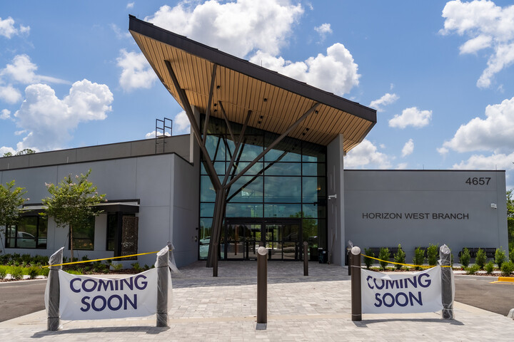 Front entrance of the Horizon West Branch library building with a modern glass façade and “Coming Soon” banners.