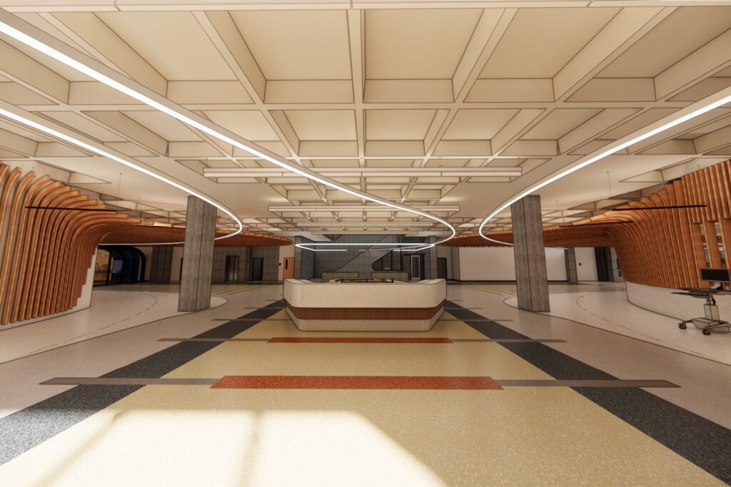 A spacious library lobby with a central information desk, geometric ceiling, curved wooden architectural elements along the walls, and multicolored flooring arranged in broad stripes.