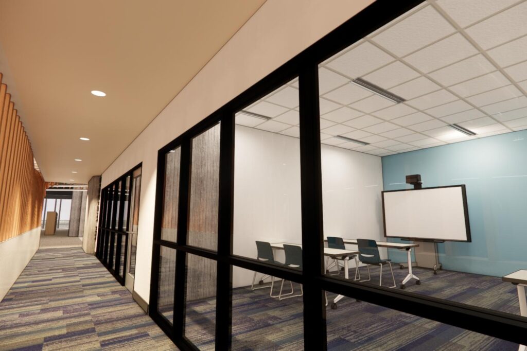 A small library program room enclosed by black-framed glass walls, containing tables and chairs arranged for a class or meeting, with a large digital screen on a light blue accent wall; the space is viewed from a softly lit hallway with patterned carpet and wood wall detailing.